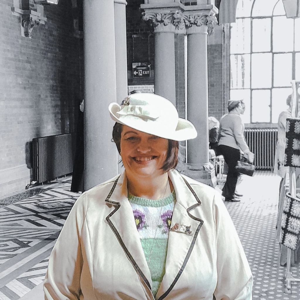 Woman in off-white 1930s short brim hat, wuth curled side and back and decorate with off-white band and bow